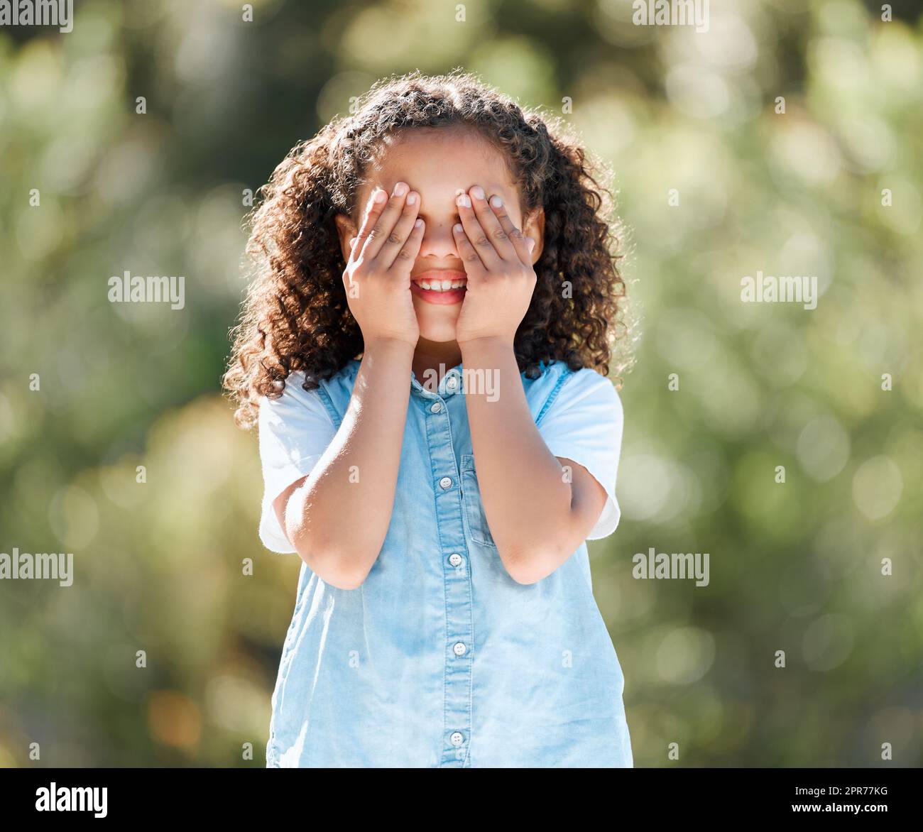 Lassen Sie spielen Verstecken und suchen. Aufnahme eines entzückenden kleinen Mädchens, das ihre Augen bedeckt, während es draußen steht. Stockfoto