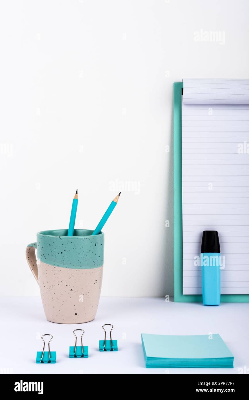Becher Mit Zwei Bleistiften Auf Dem Schreibtisch Mit Klemmbrett Mit Wichtiger Nachricht, Büroklammern, Marker Und Notizen. Tasse Mit Stiften Auf Dem Tisch Mit Memos Mit Grausamkeiten Präsentiert. Stockfoto