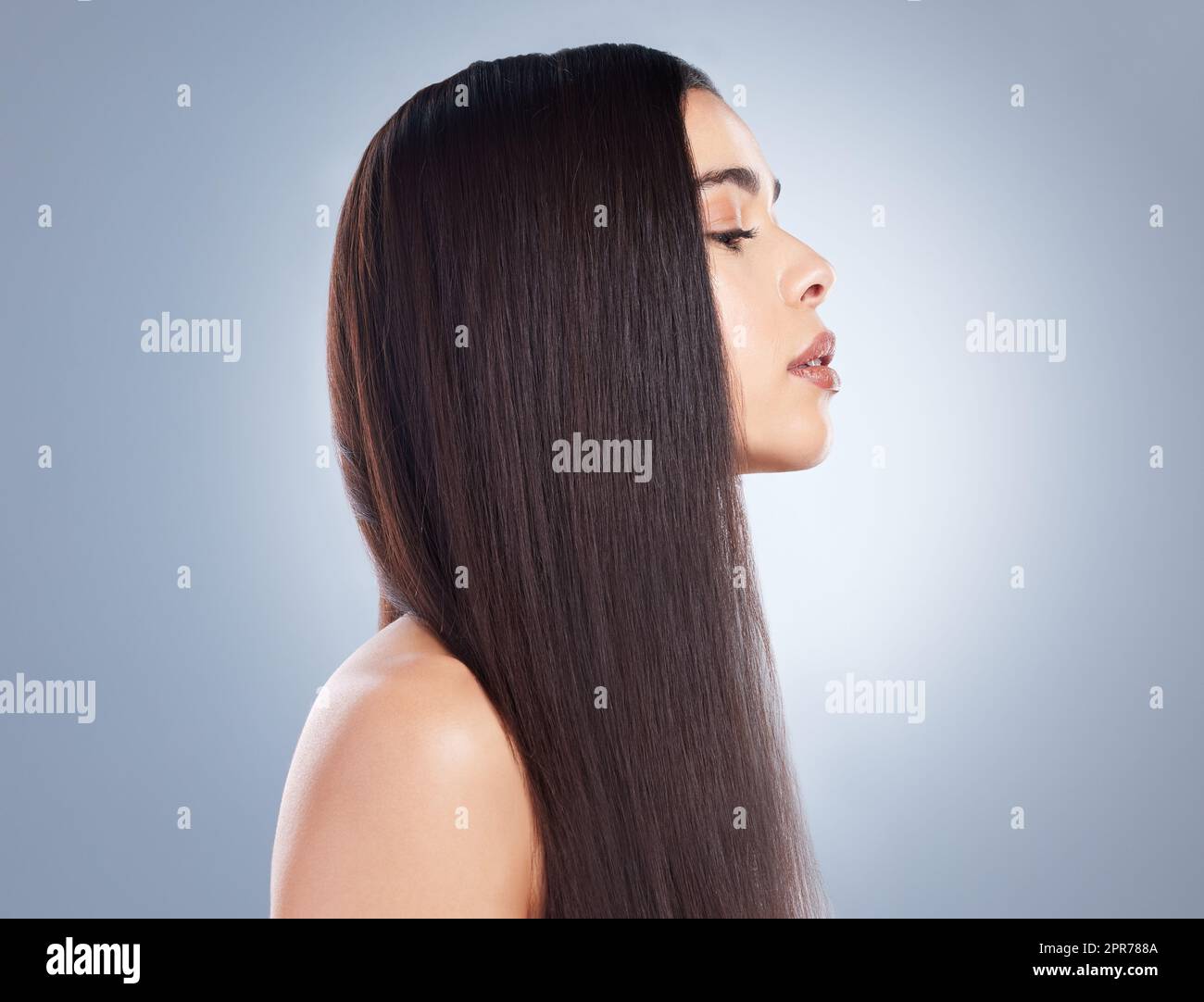 Profilansicht eines wunderschönen braunhaarigen Mädchens mit glattem und glänzendem Haar vor grauem Hintergrund. Junge brünette Frau mit schönen langen, glatten Haaren Stockfoto