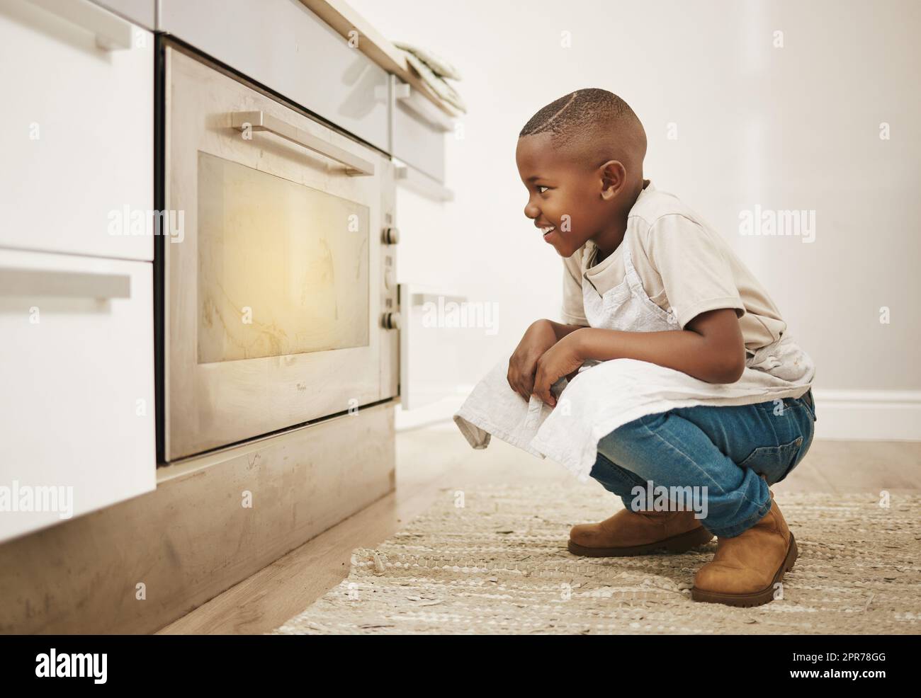 Ich kann es kaum erwarten, diese zu probieren. Aufnahme eines kleinen Jungen, der seine Backwaren zu Hause im Ofen kocht. Stockfoto