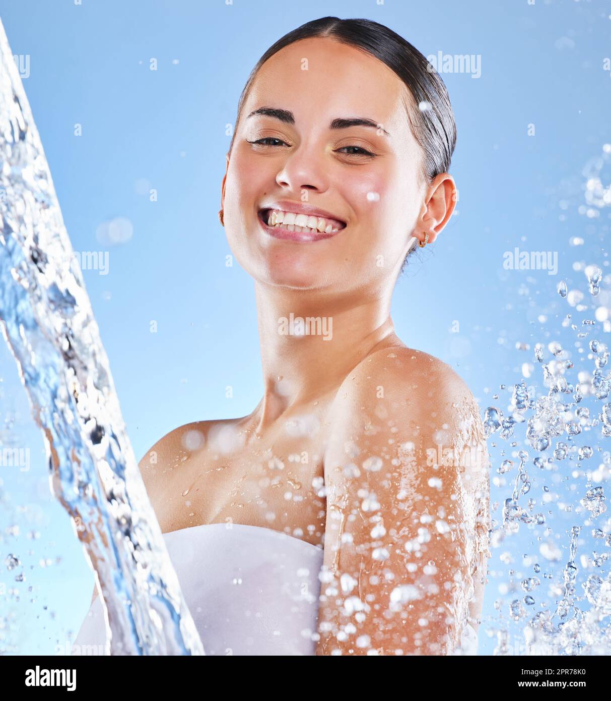 Holen Sie sich frische Zutaten. Aufnahme einer schönen jungen Frau, die vor blauem Hintergrund mit Wasser bespritzt wurde. Stockfoto