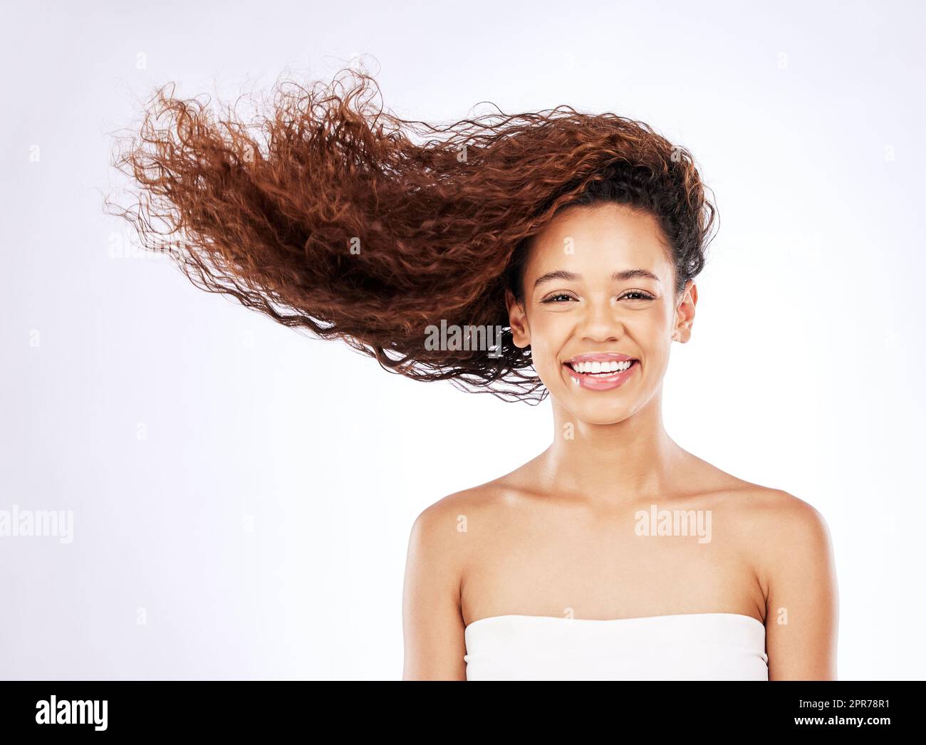 So glänzend, dass man es kaum glauben kann. Porträt einer jungen Frau mit fließenden Locken vor weißem Hintergrund. Stockfoto