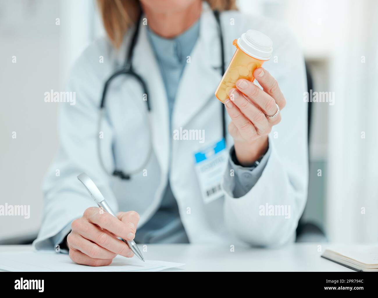 Ich habe genaue Anweisungen, wie man diese einnimmt. Freigestellte Aufnahme eines nicht erkennbaren Arztes, der allein in ihrer Klinik sitzt und Notizen schreibt, während er eine Flasche Pillen in der Hand hält. Stockfoto