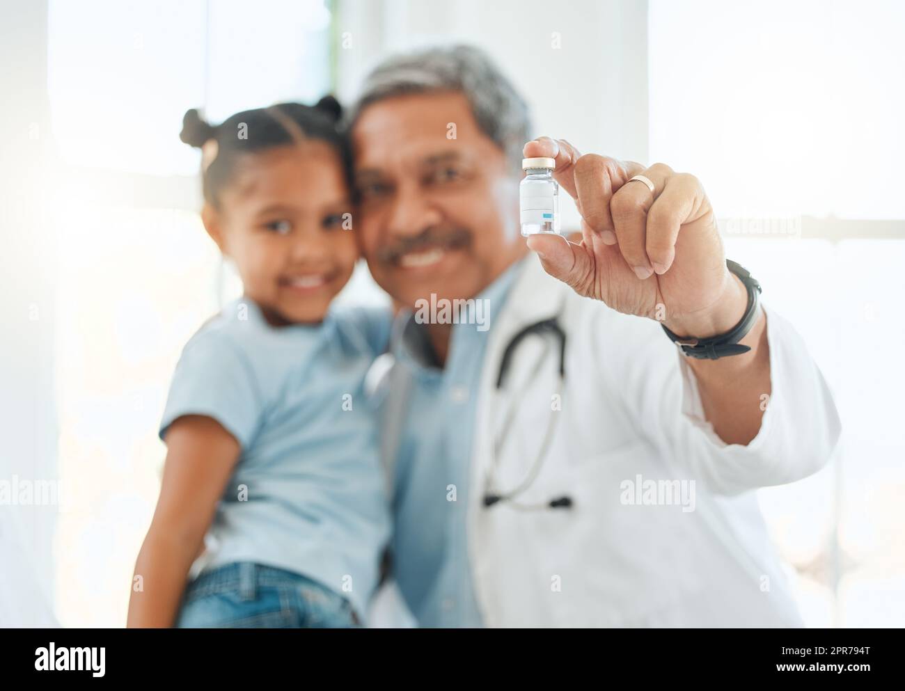 Es wird Sie vor zukünftigen Krankheiten schützen. Aufnahme eines reifen Arztes, der während einer Untersuchung mit einem kleinen Mädchen zu Hause ein Impffläschchen in der Hand hält. Stockfoto