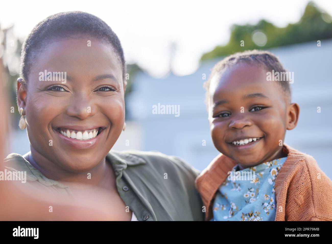 Lächeln Sie für das Selfie. Ein entzückendes kleines Mädchen, das mit ihrer Mutter in einem Garten Selfies macht. Stockfoto