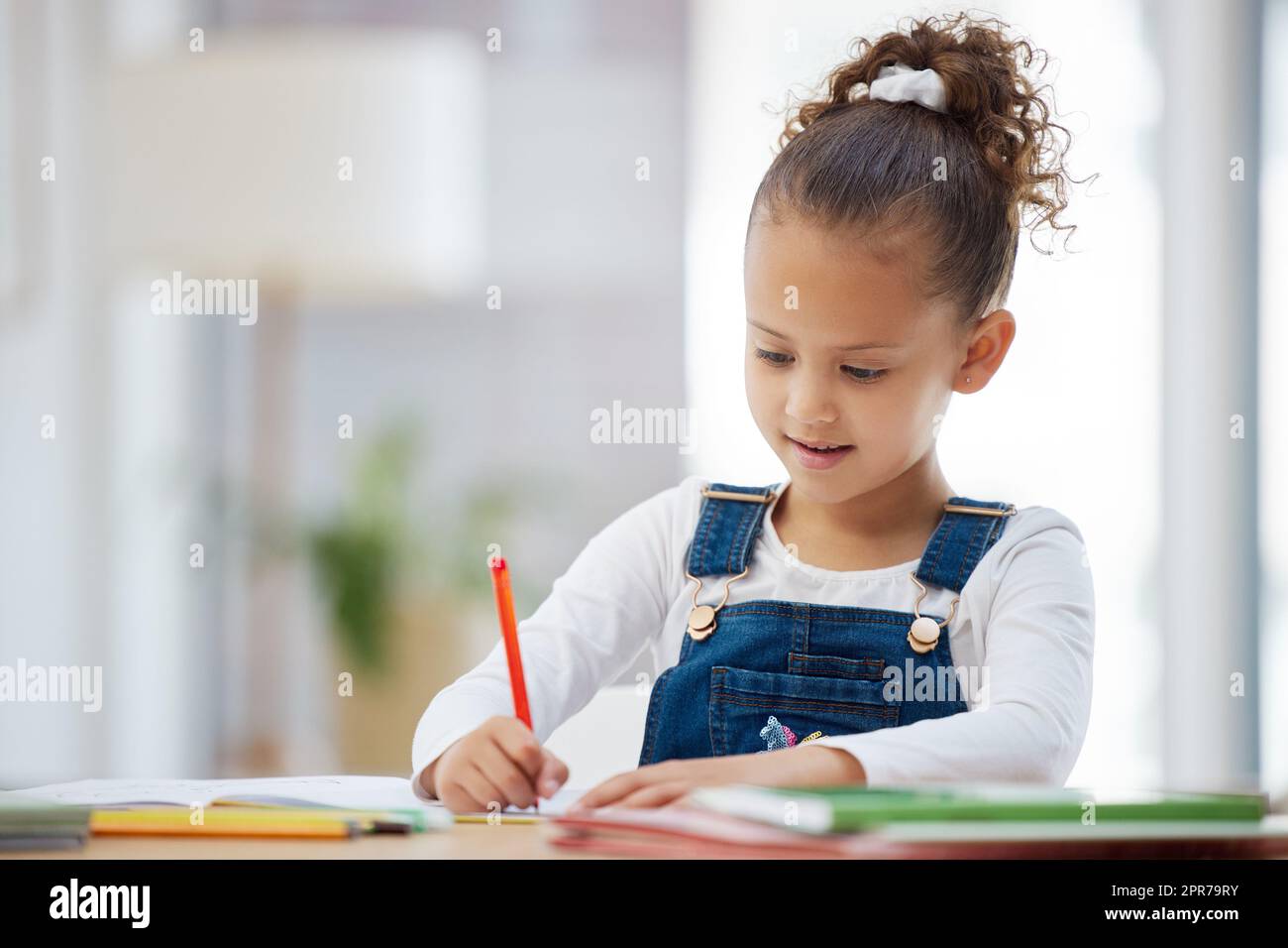 Zeit für meine Ausbildung. Ein kleines Mädchen macht Hausaufgaben zu Hause. Stockfoto