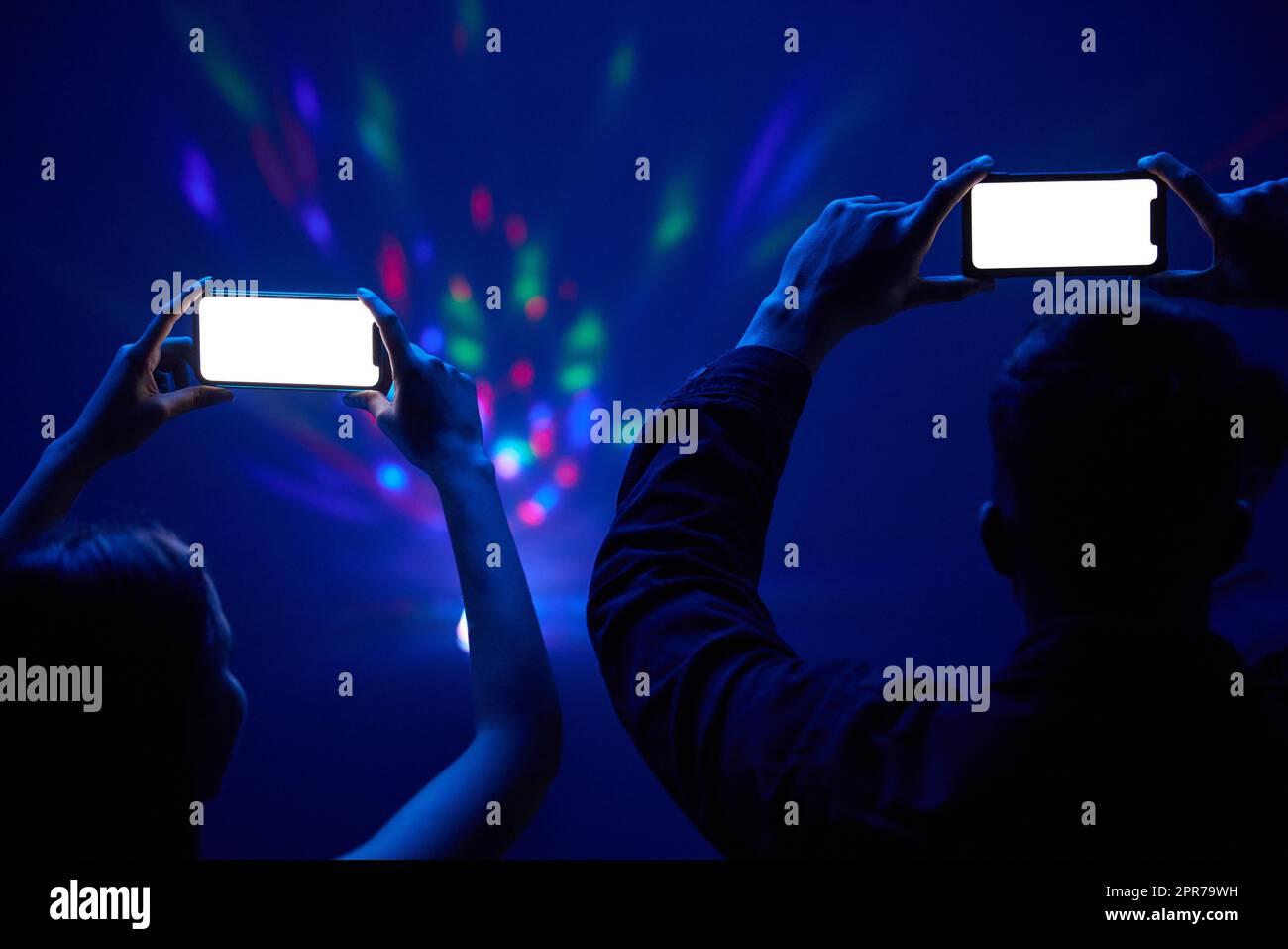 Ein unverkennbares Paar, das zusammen steht und mit dem Handy ein Konzert filmt. Stockfoto