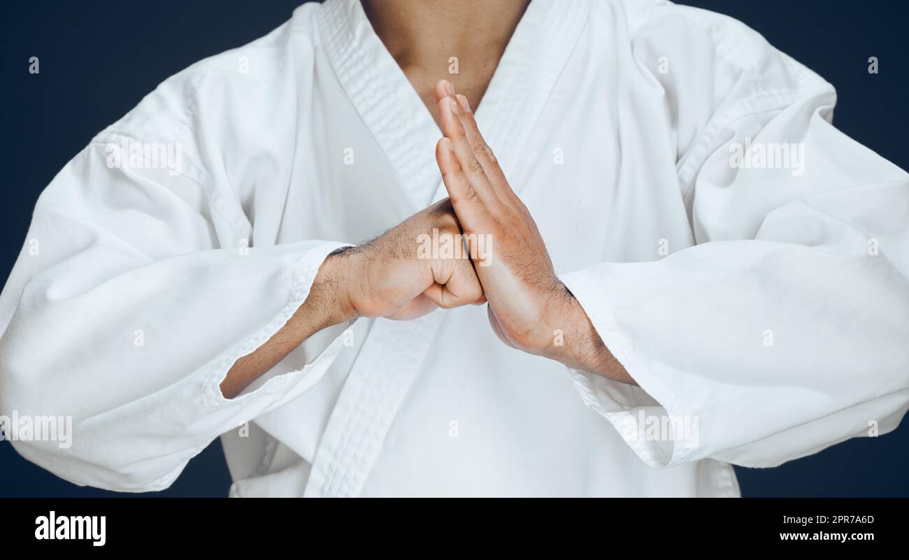 Respektvoll. Ein nicht erkennbarer männlicher Kampfkünstler übt Karate im Studio vor dunklem Hintergrund. Stockfoto