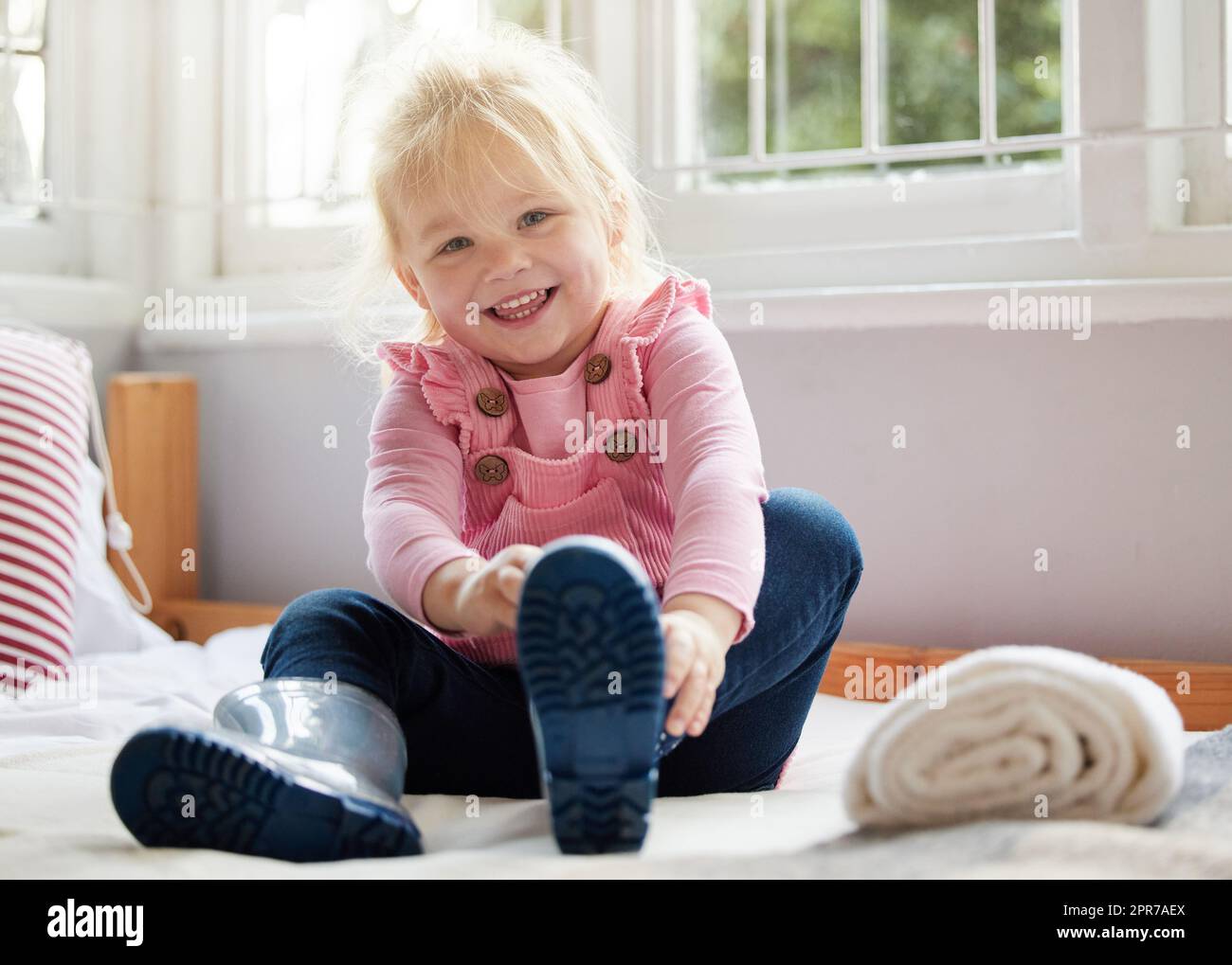 Ein kleines Mädchen, das zu Hause ihre Stiefel aufsetzt. Stockfoto