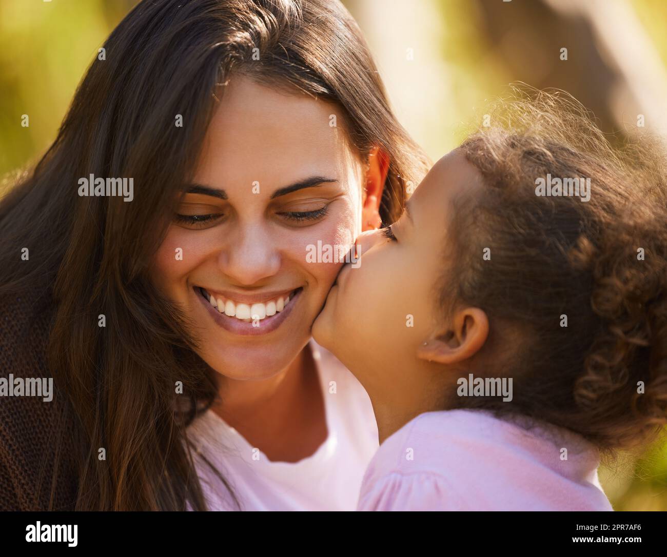 Ein Kuss für Sie. Eine attraktive junge Frau und ihre Tochter teilen sich einen intimen Moment während ihres Picknicks im Park. Stockfoto