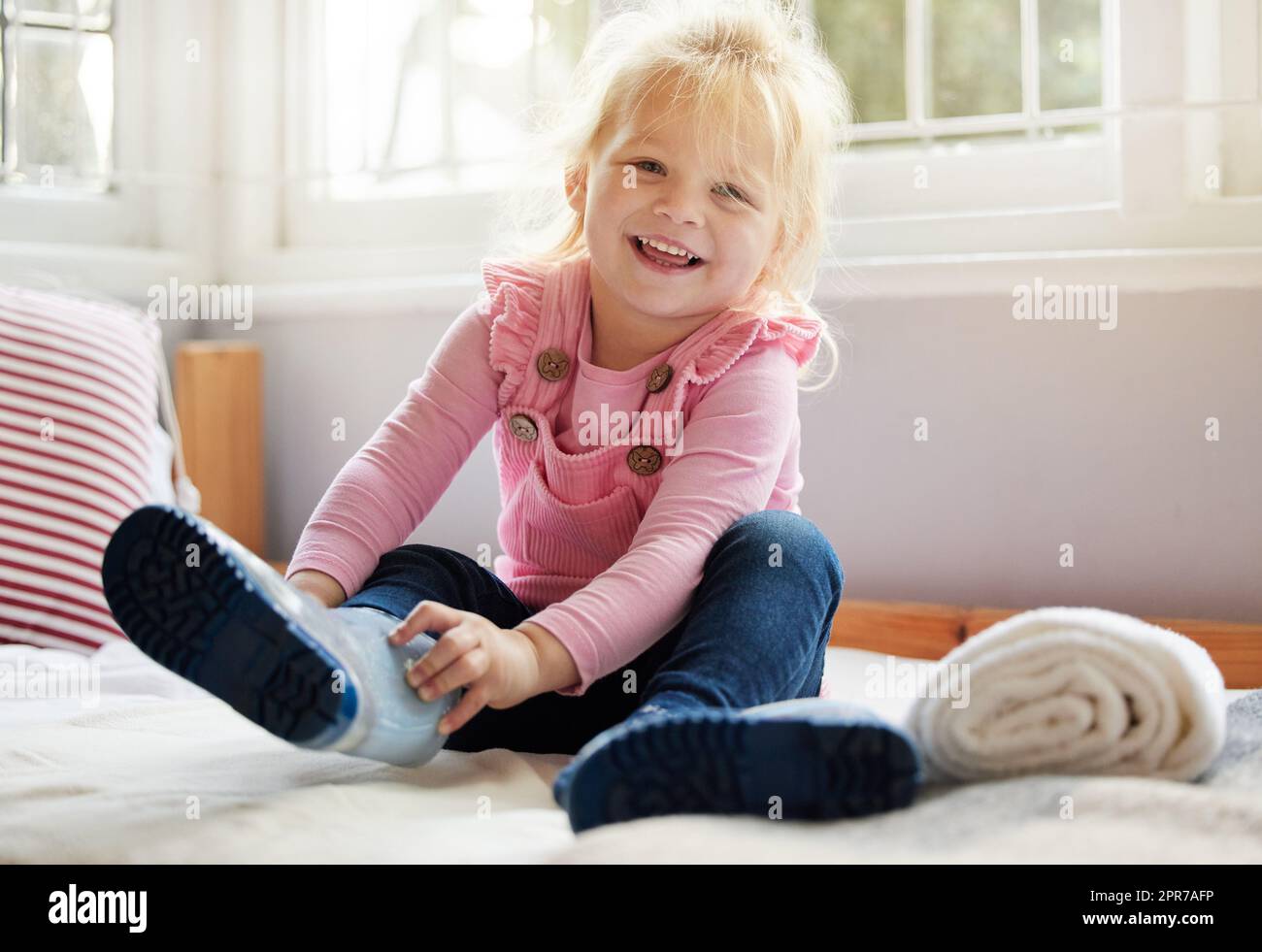 Ich bin bereit für ein Abenteuer. Ein kleines Mädchen, das zu Hause ihre Stiefel anlegt. Stockfoto
