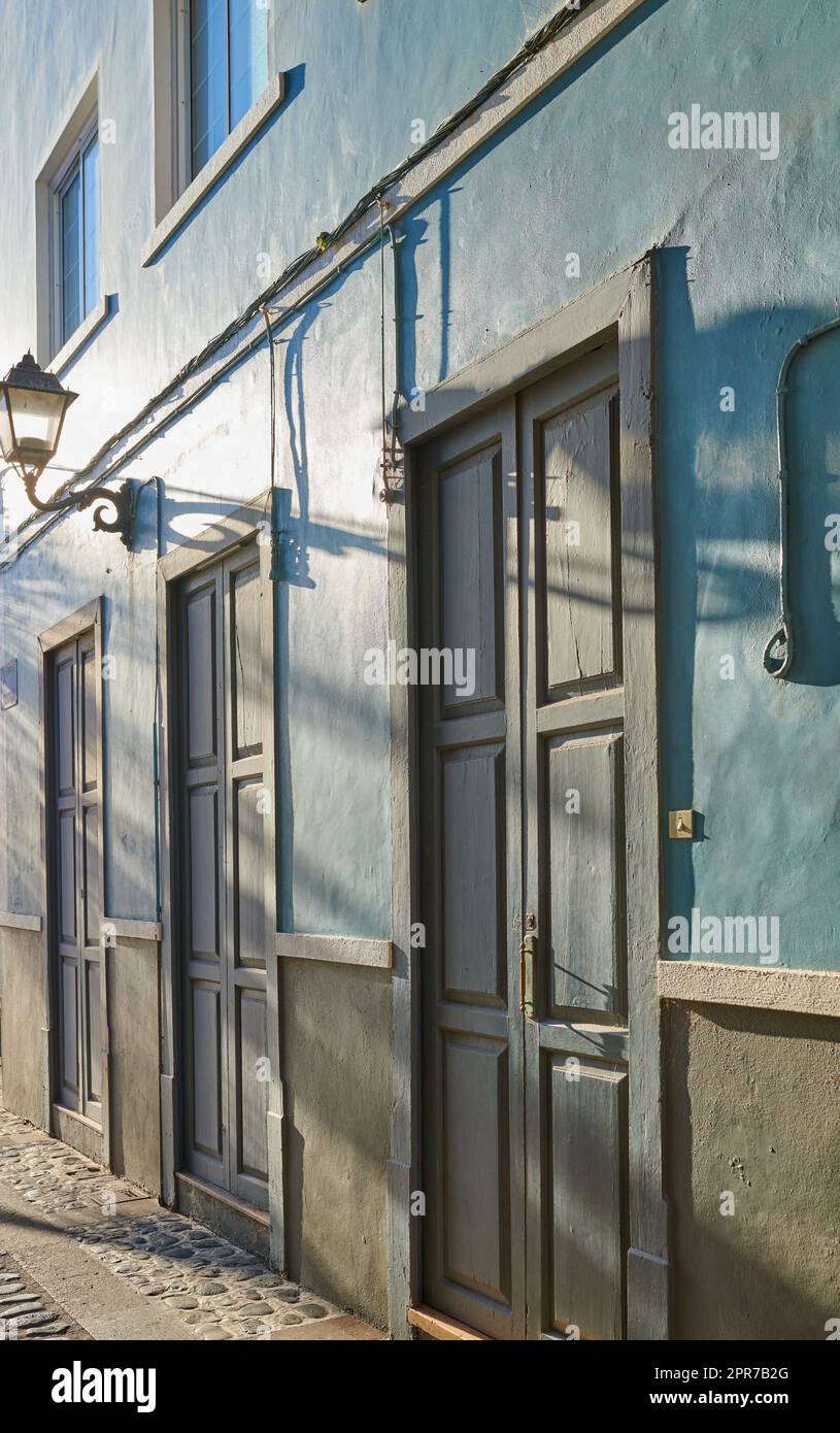 Klassische Architektur von lebhaften Gebäuden mit blauen Türen in einer Stadt. Blick aus der Nähe auf alte und traditionelle Häuser oder Häuser in einer kleinen Oldtimer-Stadt oder einem Dorf mit hellen Farben und einem einzigartigen Design Stockfoto