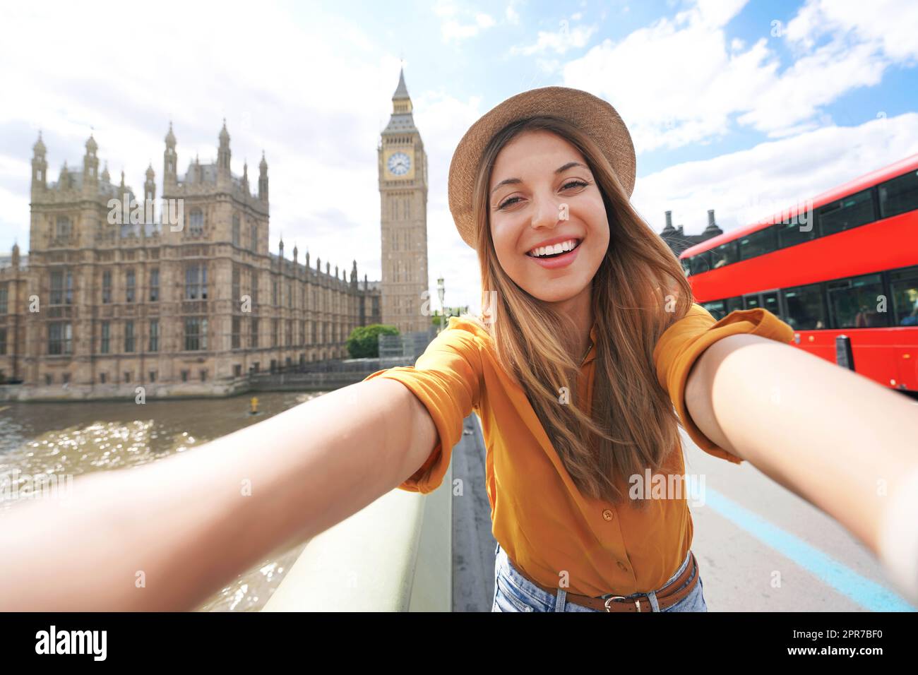 Lächelndes Touristenmädchen, das Selbstporträt in London macht. Selfie-Foto einer glücklichen Frau, die in London mit dem Big Ben Tower, dem Westminster Palace und dem roten Doppeldeckerbus an sonnigen Sommertagen reist. Stockfoto