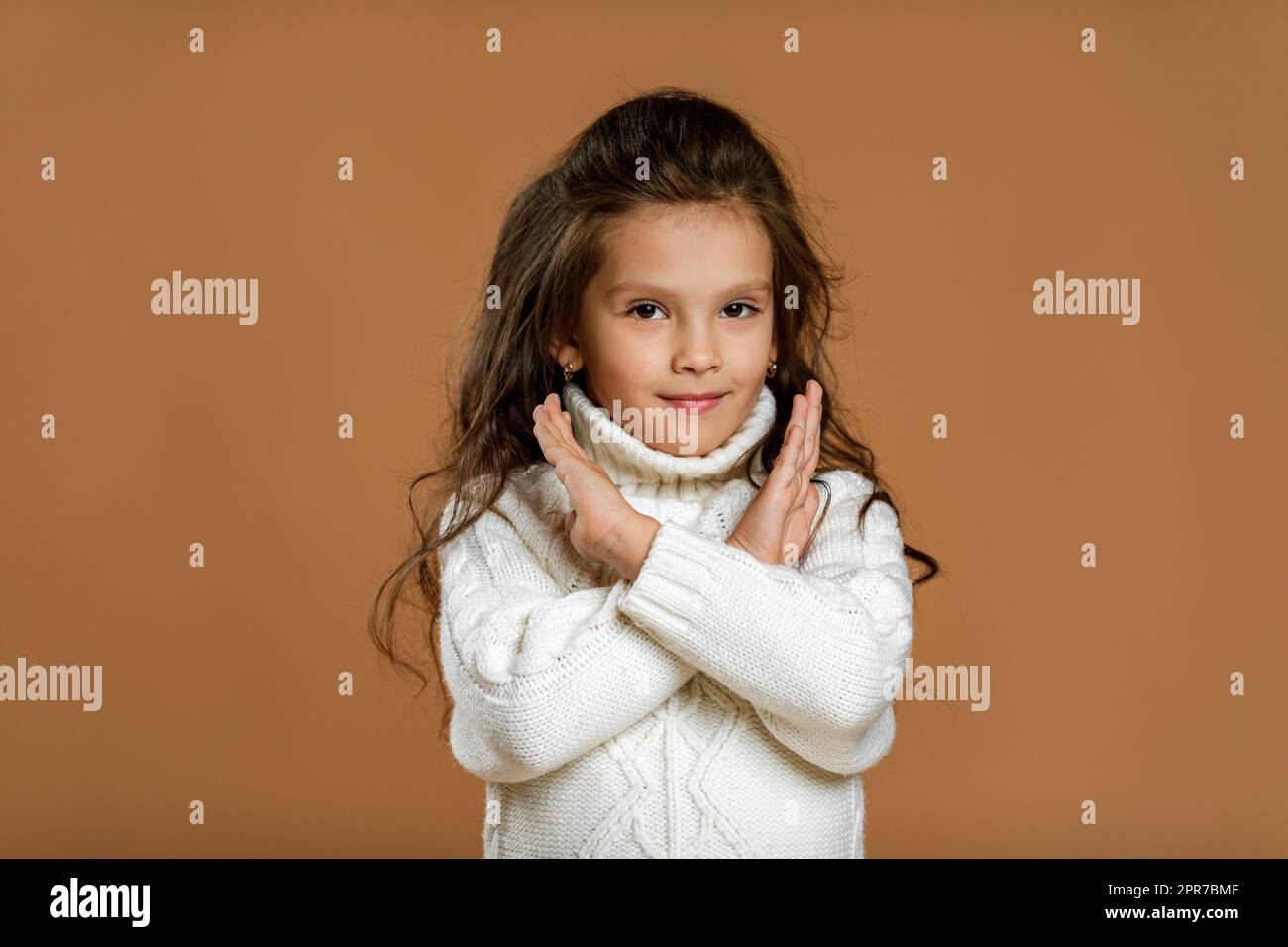 Ein kleines Mädchen im weißen Pullover, das eine Stoppbewegung macht Stockfoto