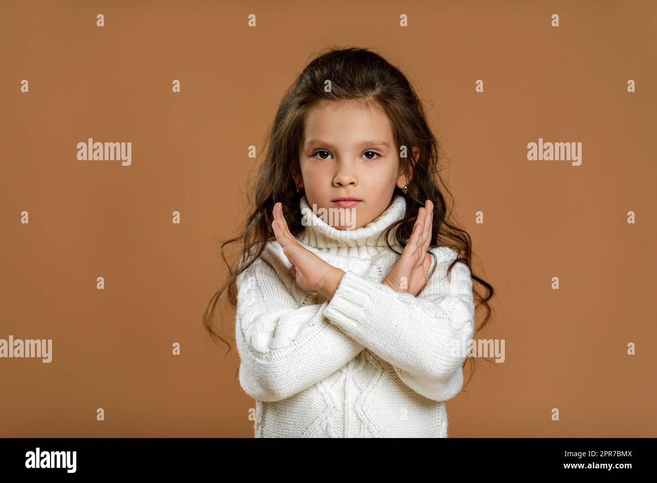 Ein kleines Mädchen im weißen Pullover, das eine Stoppbewegung macht Stockfoto