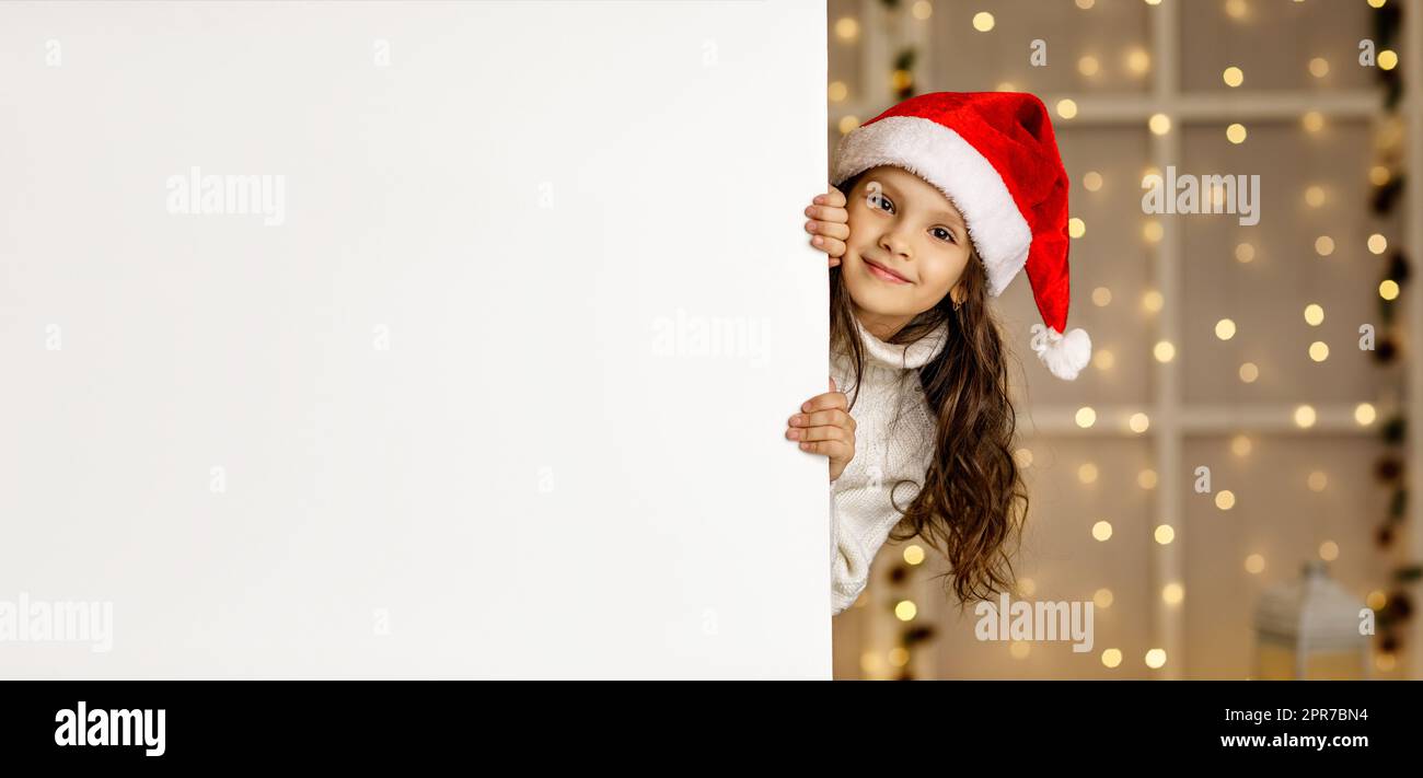 Kleines Mädchen mit rotem weihnachtsmann-Hut und weißem Banner Stockfoto