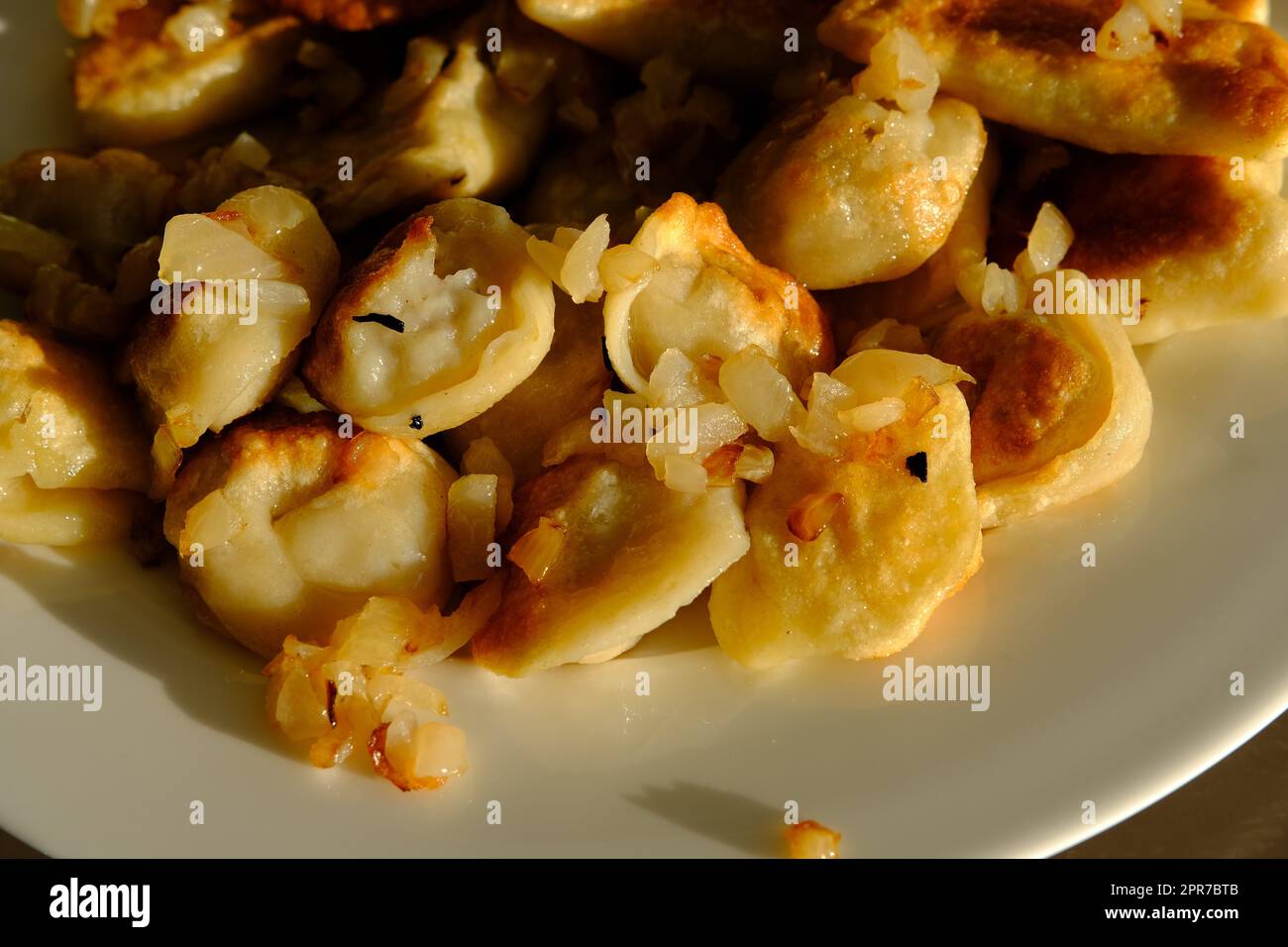 Hausgemachte Kartoffelknödel oder Vereniki-Pierogi, serviert mit gebratenen Zwiebeln. Rustikaler Stil, komfortable osteuropäische Küche Stockfoto