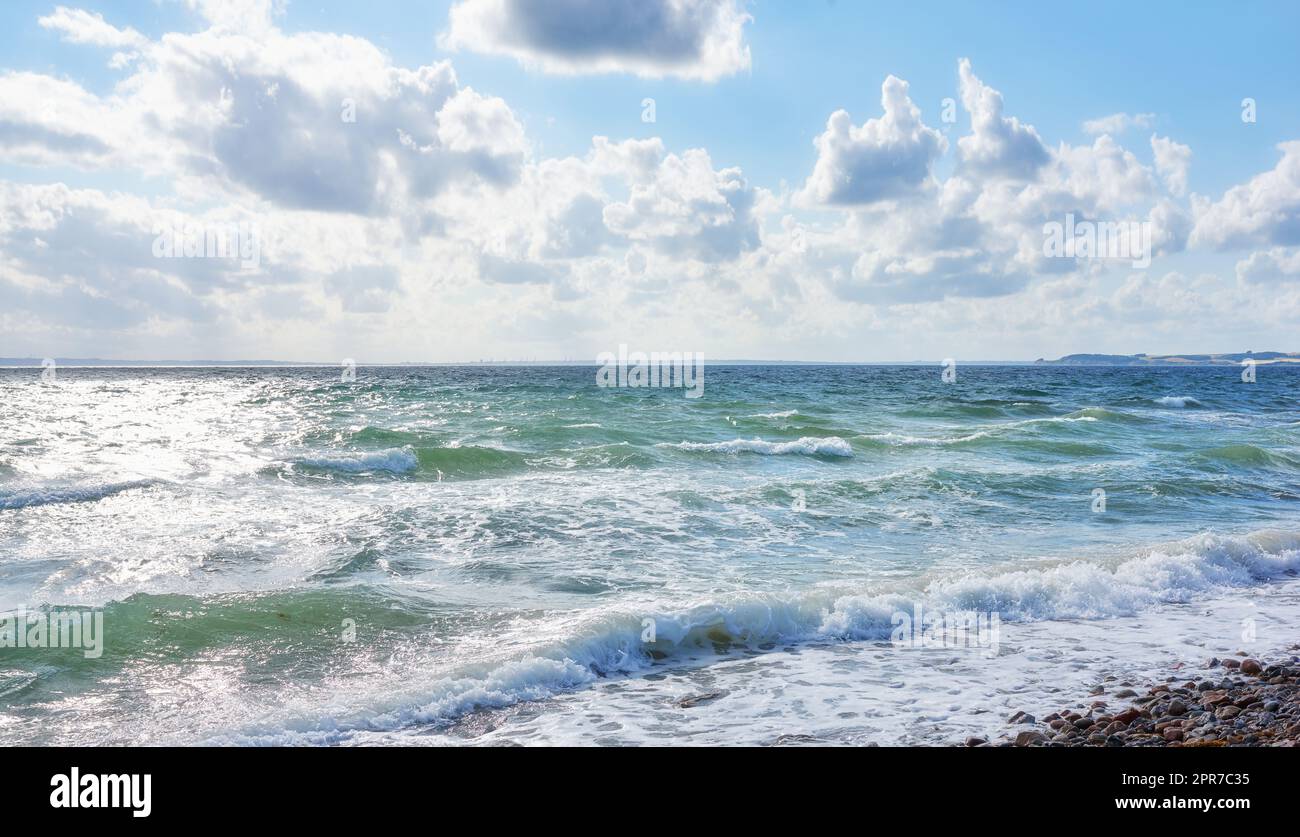Küste von Kattegat - Helgenaes, Dänemark. Ozeanwellen, die sich auf das leere Strandufer spülen. Ruhiges, friedliches Paradies der Sommerlandschaft und des Himmels für einen erholsamen Urlaub im Ausland oder einen Urlaub im Ausland Stockfoto