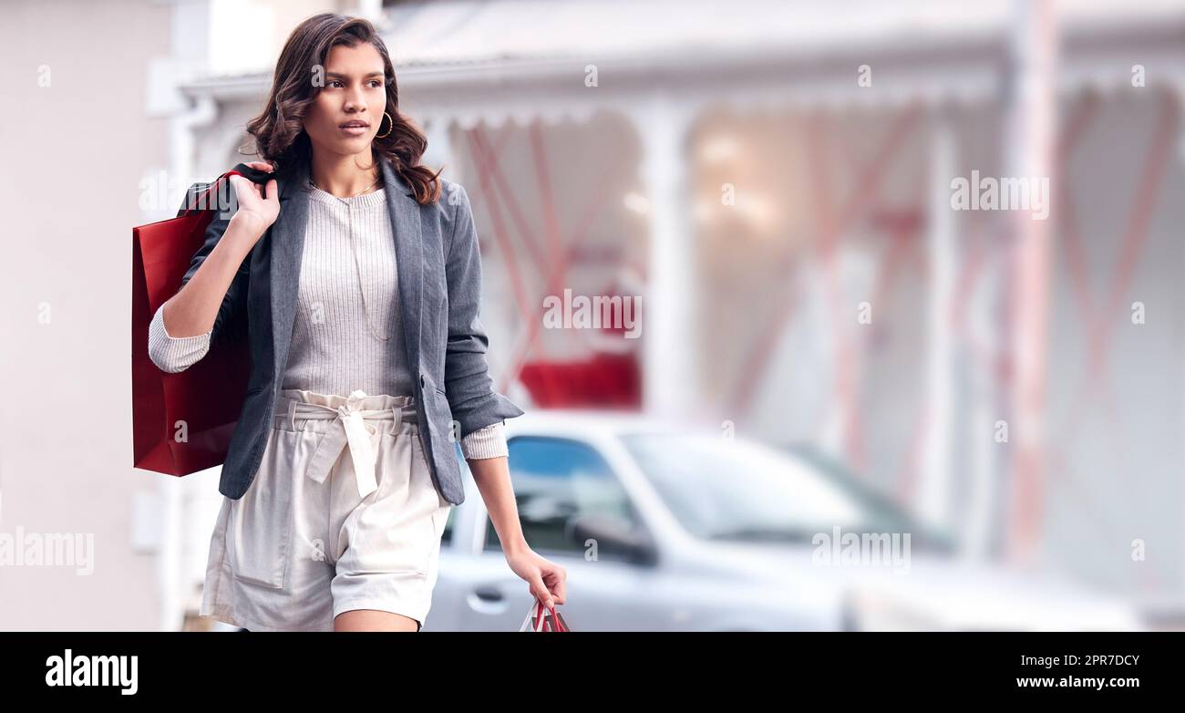 Das Leben ist hart, Einkaufen hilft. Eine junge Frau, die mit Einkaufstaschen durch die Stadt läuft. Stockfoto