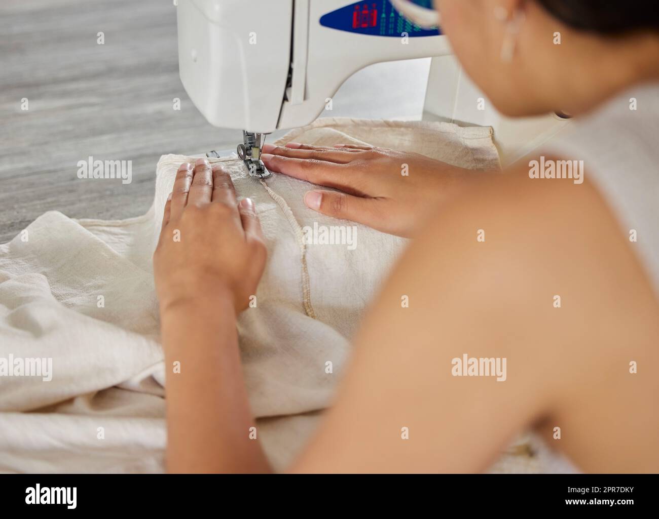 Annähen und annähen. Rückansicht einer Frau, die in ihrer Werkstatt eine Nähmaschine benutzt. Stockfoto