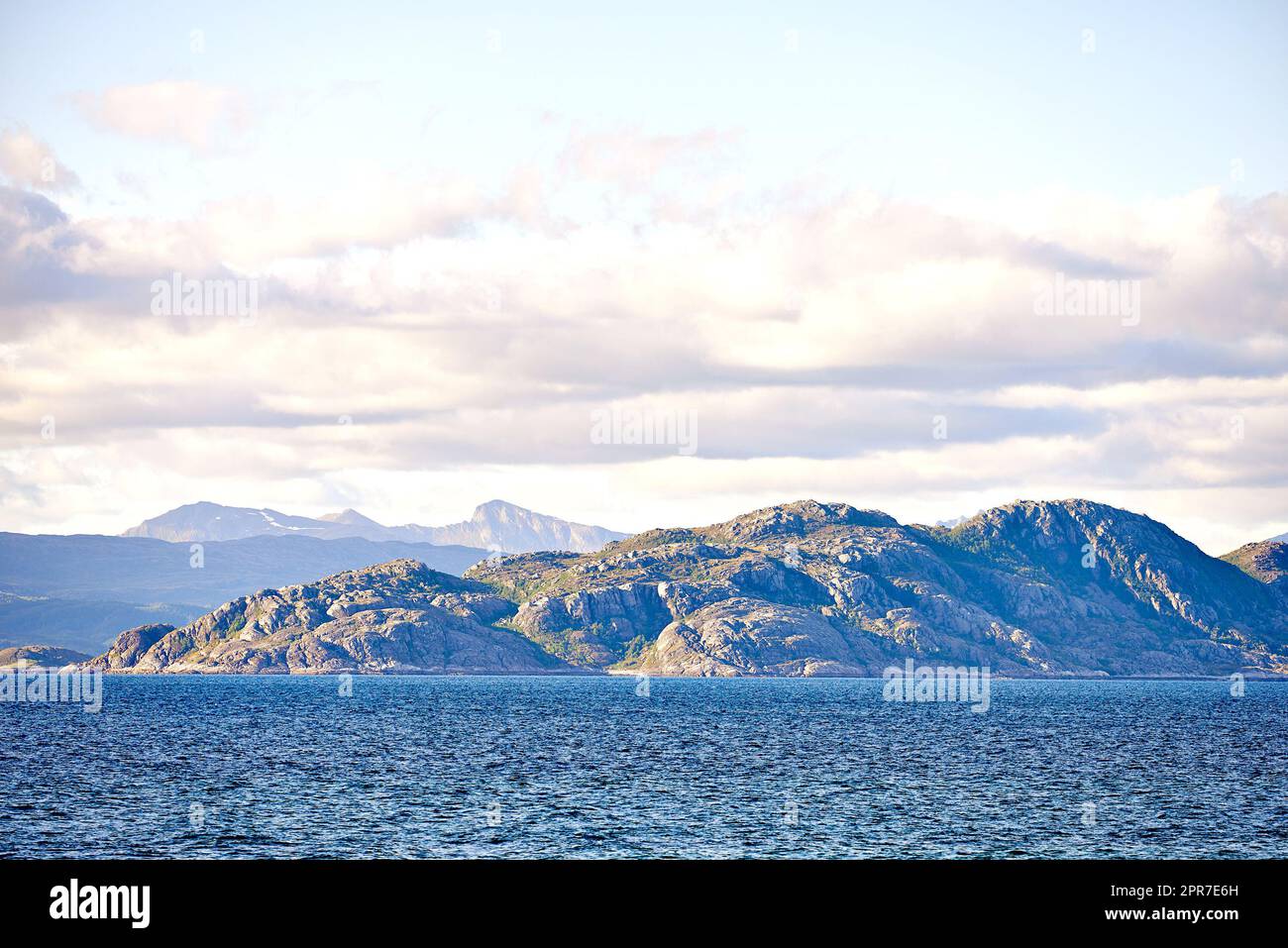 Malerischer Blick auf das Meer, die Berge, Felsen und Felsen in Norwegen. Gezeiten-Ozean-Wasserwellen, blauer Himmel mit Wolken und Kopierraum. Reisen und Tourismus im Ausland und im Ausland zu einem abgelegenen und friedlichen Reiseziel Stockfoto