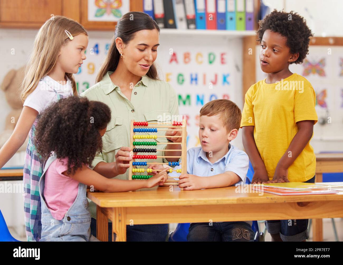 Der Kindergarten bietet eine Grundlage für das soziale und akademische Lernen. Aufnahme einer jungen Frau, die eine Klasse von Vorschulkindern unterrichtet. Stockfoto