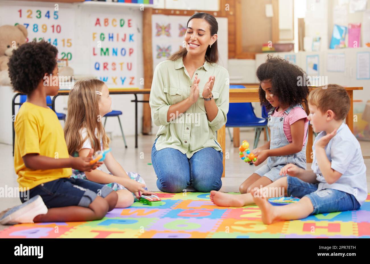 Wenn du glücklich bist und es weißt, klatsche in die Hände. Aufnahme einer Lehrerin, die mit ihren Vorschulkindern singt. Stockfoto