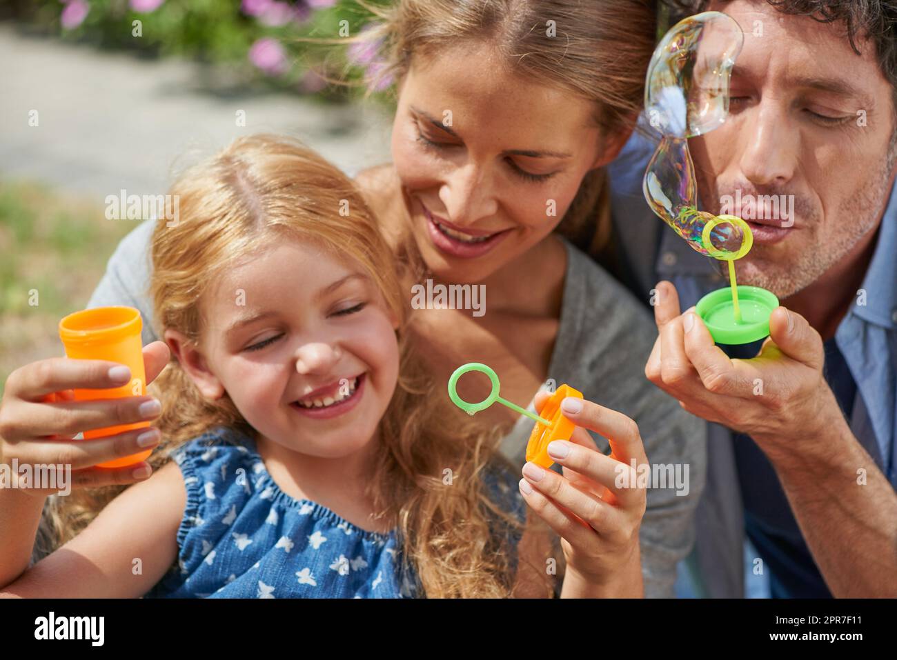 Spaß in der Sonne mit ihnen. Aufnahme einer jungen Familie, die zu Hause Blasen bläst. Stockfoto
