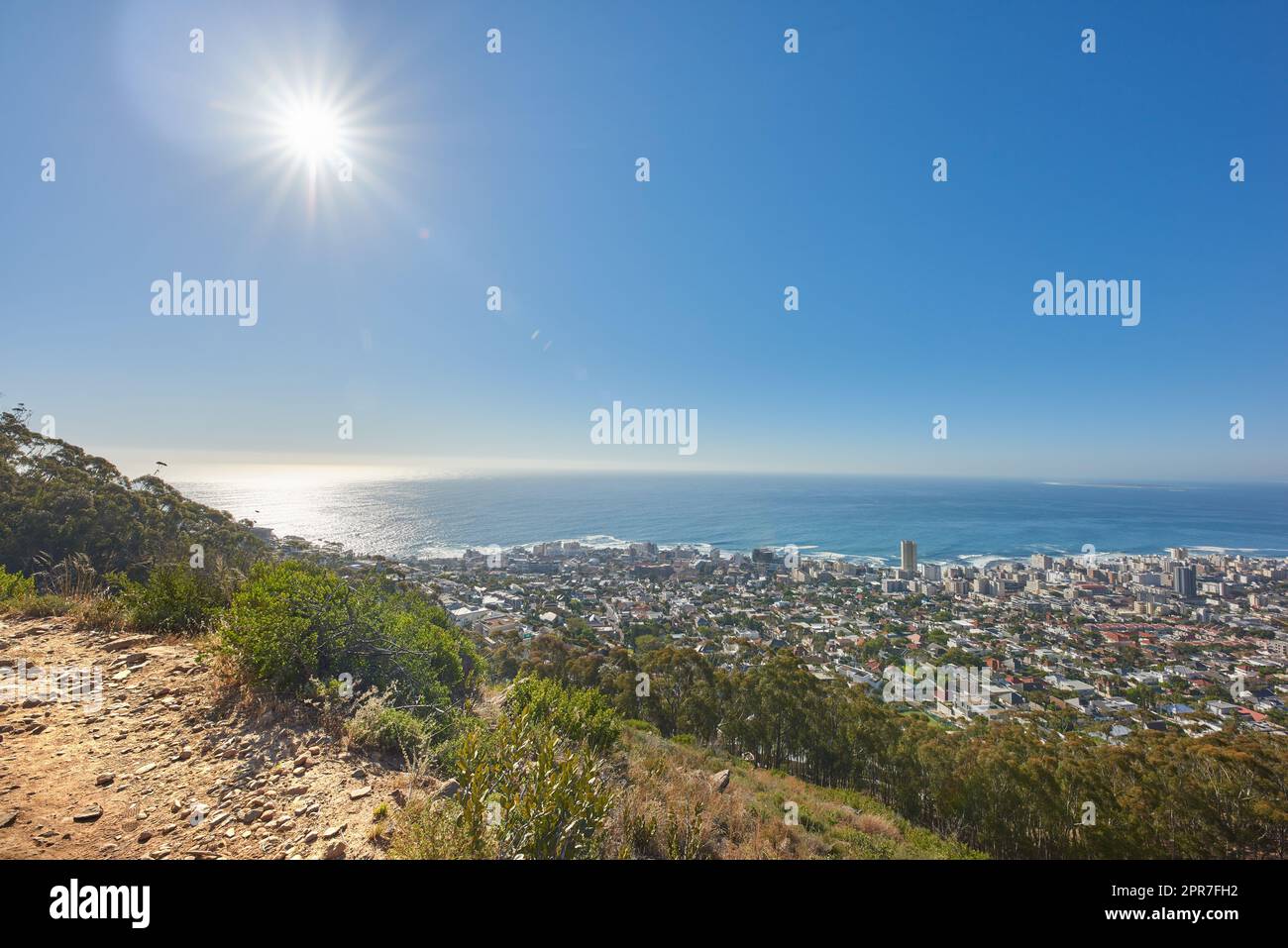 Copy Space mit Blick vom Tafelberg in Kapstadt Südafrika auf einen klaren blauen Himmel über einer Küstenstadt. Malerische Landschaft mit Gebäuden in einer Stadt entlang der Berge und des Meeres an einem sonnigen Tag Stockfoto