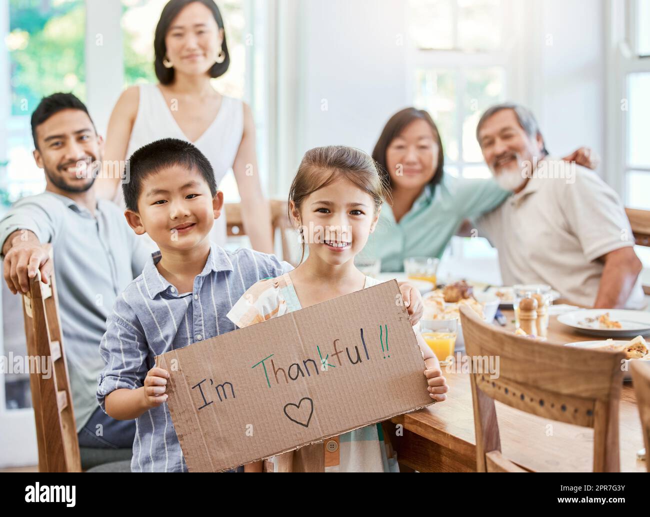 Wer auch immer Sie sind, Sie brauchen Familie. Aufnahme eines kleinen Mädchens mit einem Schild beim Mittagessen zu Hause. Stockfoto