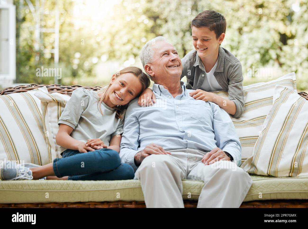 Meine Enkel meinen mir die Welt. Aufnahme eines älteren Mannes, der mit seinen beiden Enkeln draußen sitzt. Stockfoto