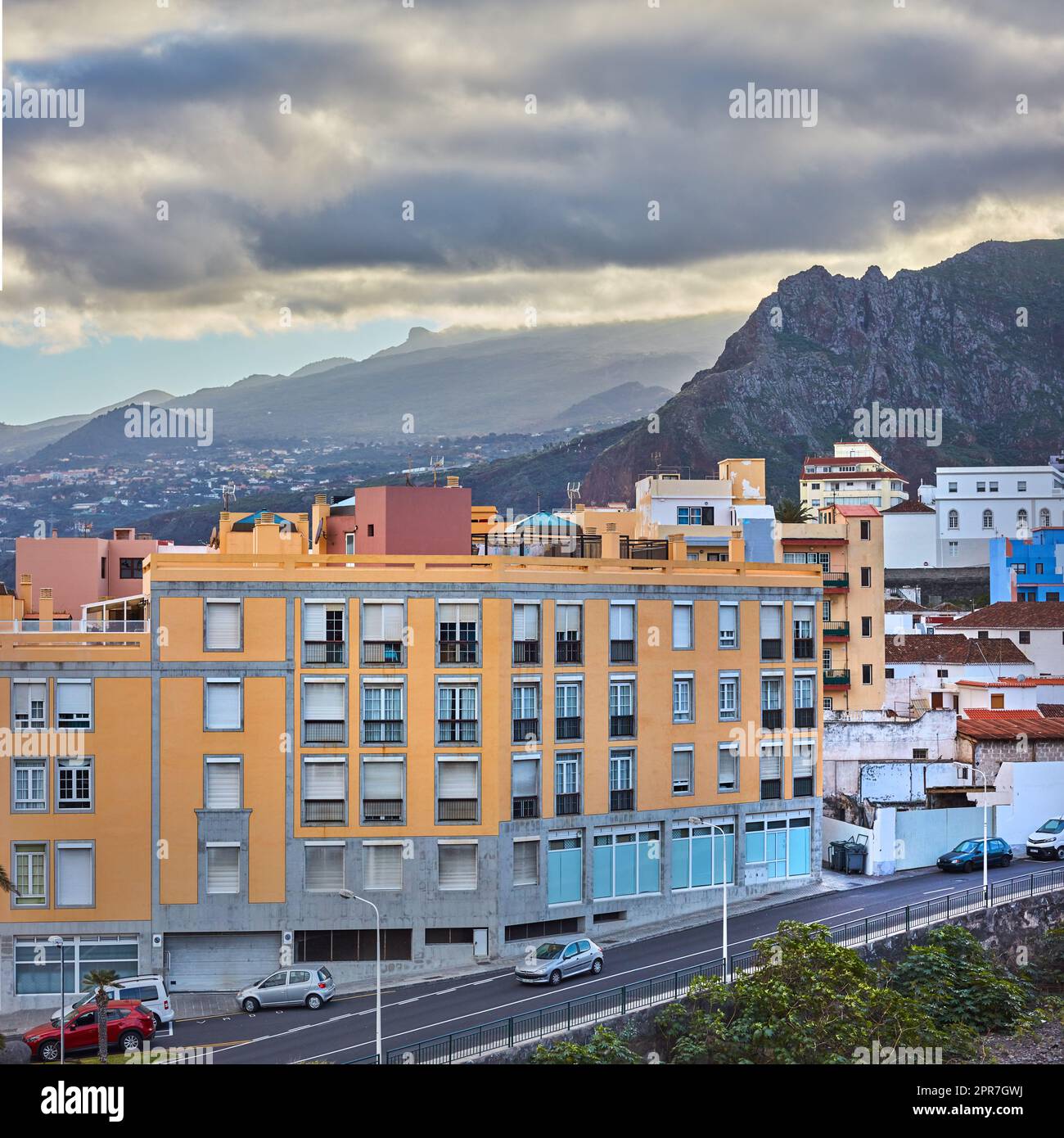 Malerischer Landschaftsblick auf lebendige Häuser, traditionelle Wohngebäude oder Stadtstrukturen. Touristenziel Straße auf der Santa Cruz Straße, La Palma, Spanien mit Bergen im Hintergrund und bewölktem Himmel Stockfoto
