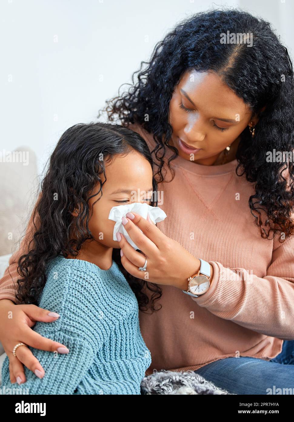 Eine Mutter wird sich um Sie kümmern. Eine junge Mutter hilft ihrer Tochter, sich zu Hause die Nase zu blasen. Stockfoto