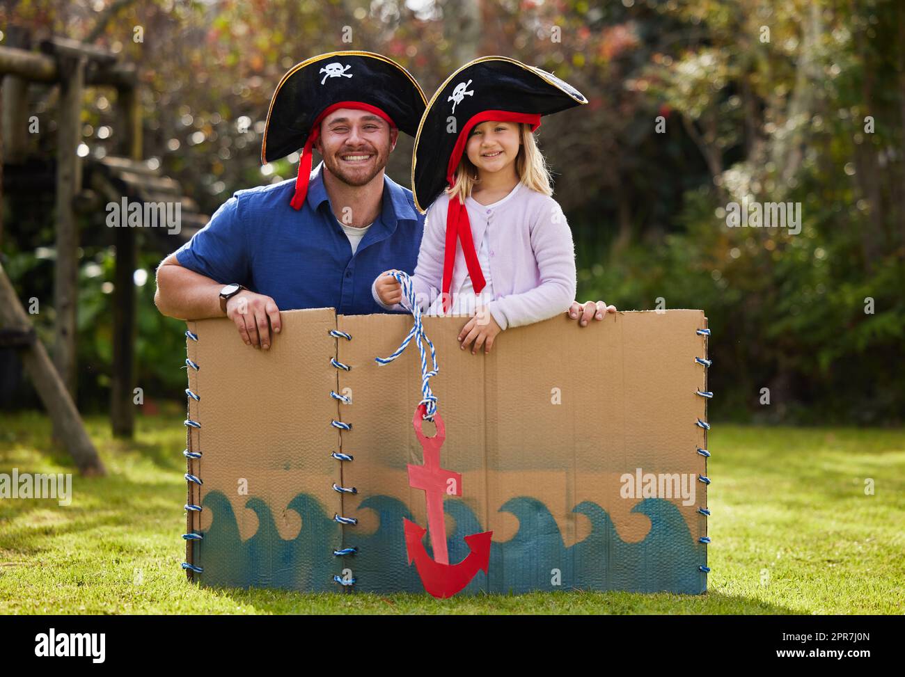 Lasst uns an Bord springen und sie in Stücke schneiden. Ein Vater und eine Tochter, die sich draußen im Hof wie Piraten verkleidet haben. Stockfoto