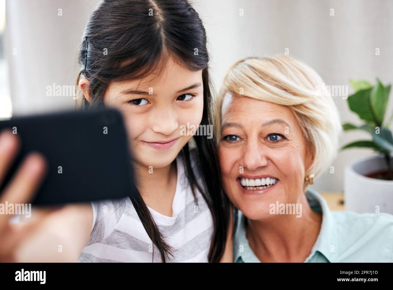 Mein Handy ist voller Bilder wie diese. Ein kleines Mädchen, das zu Hause mit ihrer Großmutter ein Selfie macht. Stockfoto
