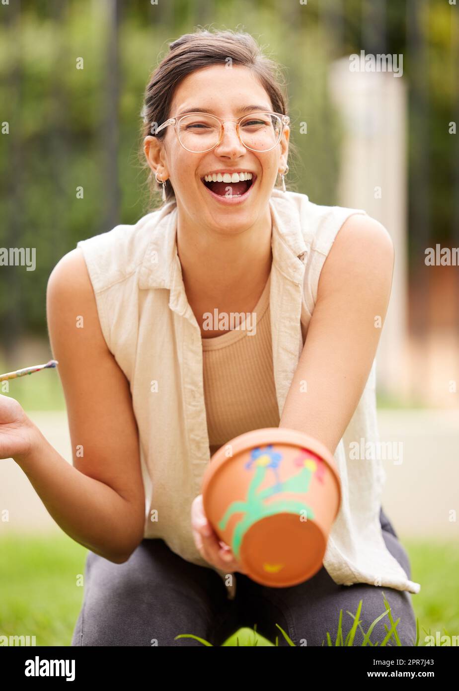 Wenn Kreativität erblüht, strahlt das Denken aus. S junge Frau, die zu Hause einen Topf im Garten malt. Stockfoto