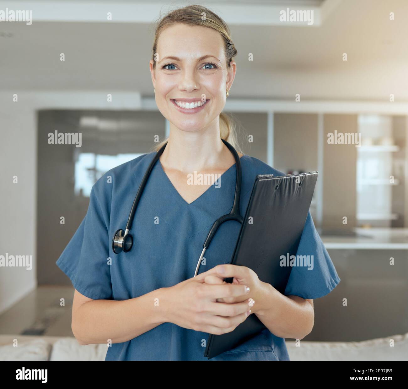 Ein hübscher junger Arzt, der glücklich und freundlich aussah, während er auf der Arbeit wartete. Lächelnder weißer Gesundheitsfachmann, der ein Stethoskop trägt und eine Mappe in der Hand hält Stockfoto