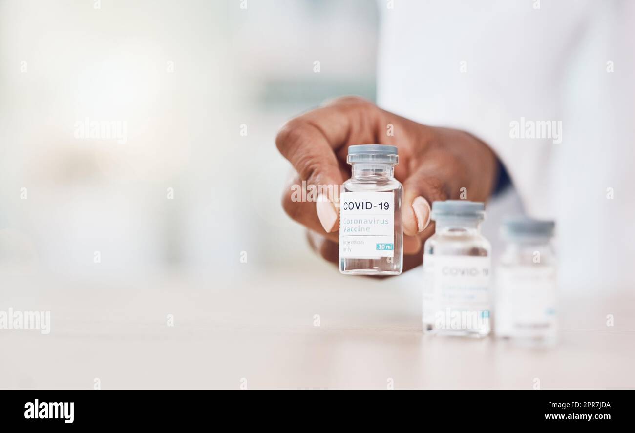 Nahaufnahme Hand der afroamerikanischen Ärztin stellt Flaschen des Corona-Virus-Impfstoffs auf, während sie in ihrer Krankenhauspraxis arbeitet. Seien Sie während des Ausbruchs der Pandemie sicher. Stoppt die Ausbreitung von Covid 19 Stockfoto