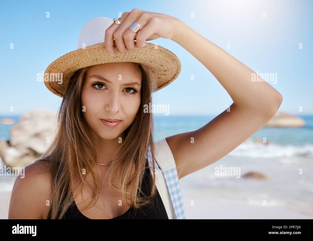 Eine wunderschöne junge weiße Frau, die sich am Strand entspannt. Genießen Sie einen Sommerurlaub oder einen Urlaub im Freien im Sommer. Sich frei nehmen und dem Alltag entfliehen. Den Tag alleine draußen zu verbringen Stockfoto