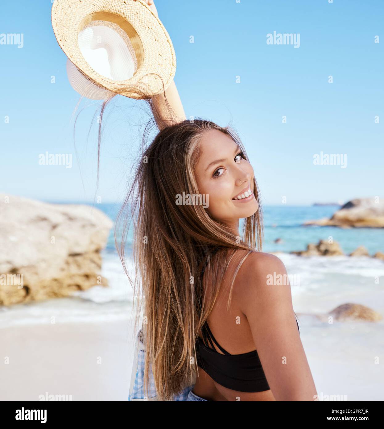 Eine wunderschöne junge weiße Frau, die sich am Strand entspannt. Genießen Sie einen Sommerurlaub oder einen Urlaub im Freien im Sommer. Sich frei nehmen und dem Alltag entfliehen. Den Tag alleine draußen zu verbringen Stockfoto