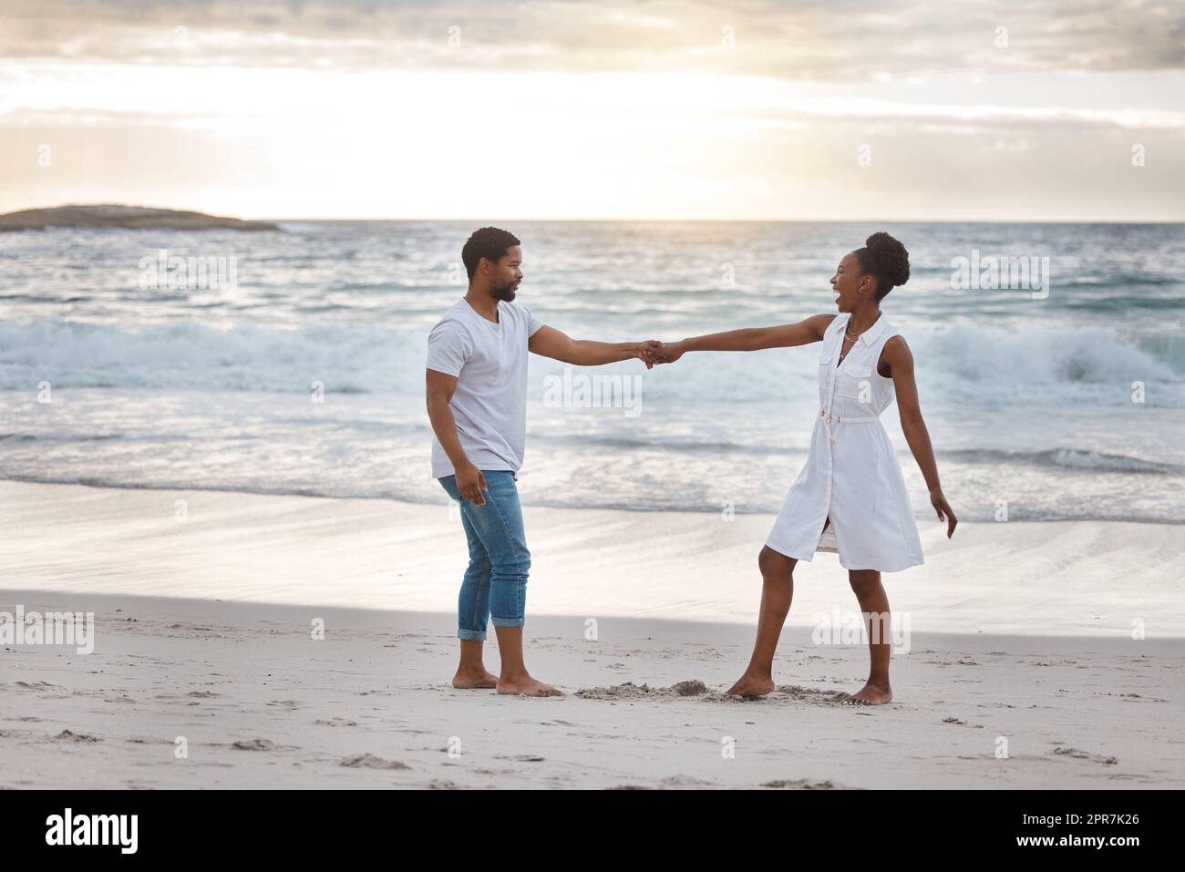 Ein verspieltes afroamerikanisches Paar, das einen Tag am Meer verbringt. Fröhlicher Freund und Freundin tanzen am Strand. Liebevoller Mann und Frau, die sich am Meer anfreunden Stockfoto