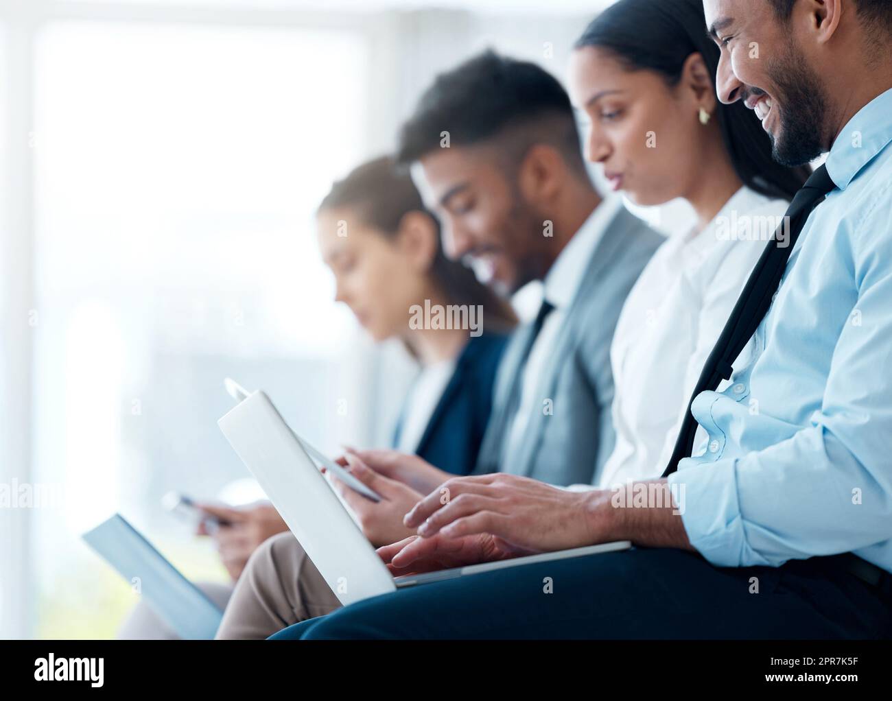 Legen Sie Ihr Projekt in die Hände dieses dynamischen Teams. Geschäftsleute in einer Gruppe sitzen und verwenden ihren Laptop, während sie auf ein Interview im Büro warten. Stockfoto