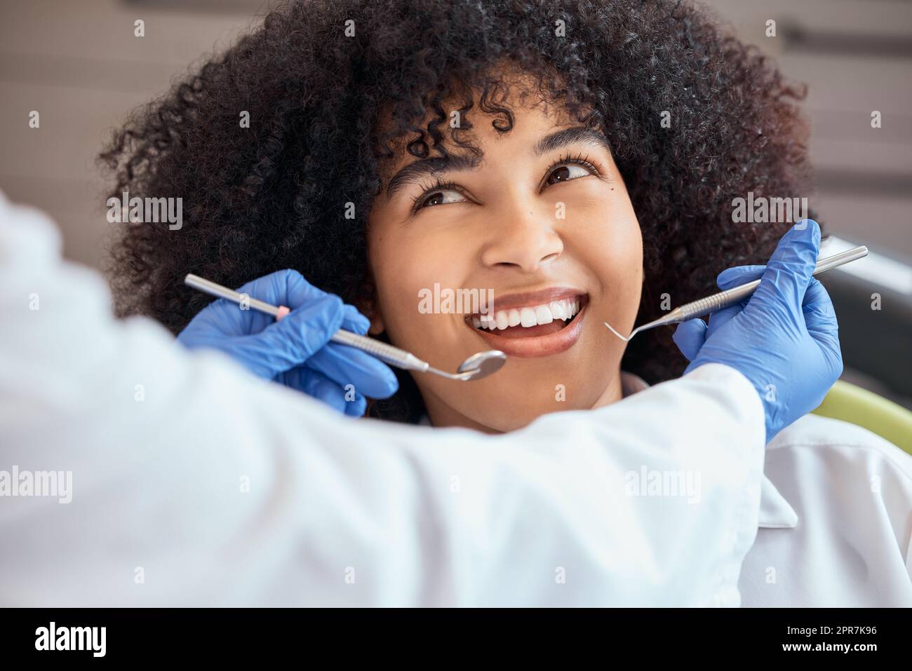 Über dem Bild einer wunderschönen jungen afroamerikanischen Frau mit einem Afro, die sich den Zahnarzt bei ihrem Zahnarzttermin ansieht. Sie muss untersucht werden, um Zahnfleischverfall und Zahnfleischerkrankungen zu verhindern. Mund- und Zahnhygiene Stockfoto