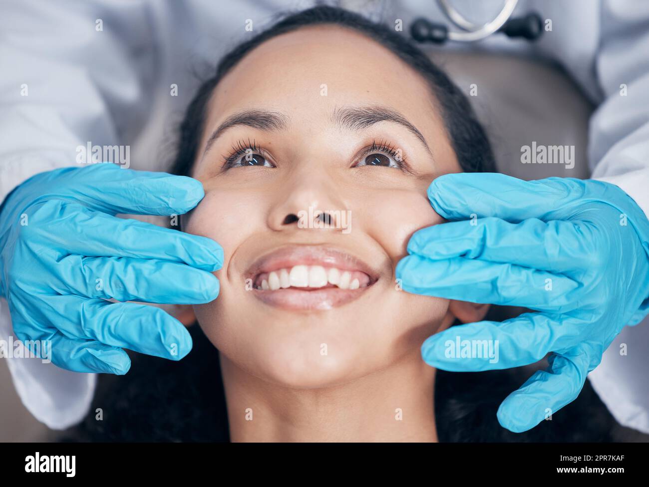 Ein Lächeln, das funkelt. Ein Zahnarzt, der nach einem Eingriff seine Handarbeit überprüft. Stockfoto