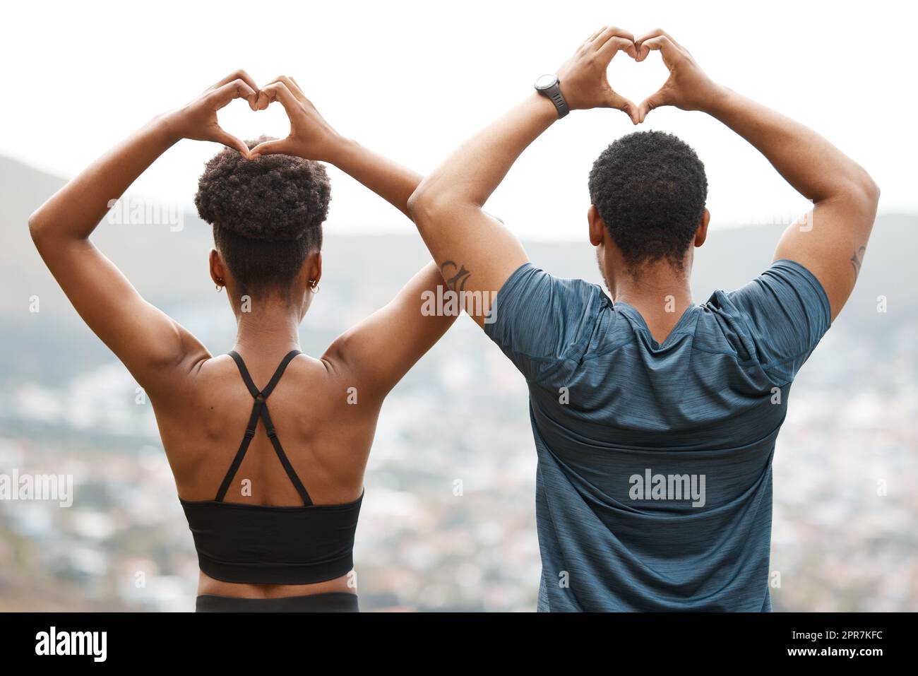 Die Rückansicht passt sich dem afroamerikanischen Paar an, das beim Sport im Freien mit den Händen Herzformen Formen lässt. Junger sportlicher Mann und junge sportliche Frau, die Gesundheit und Fitness im Freien fördern. Sie trainieren gern zusammen Stockfoto