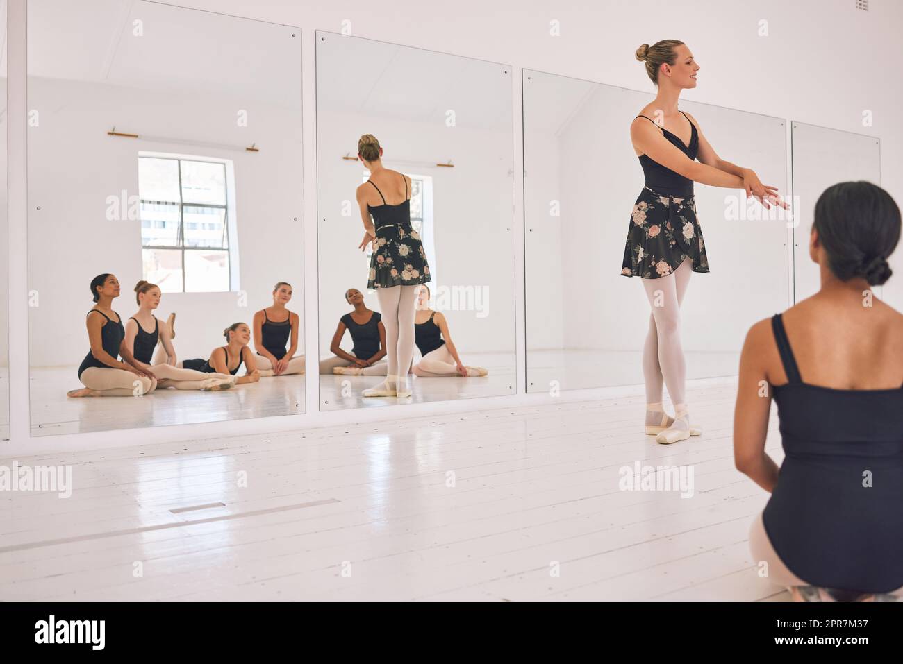 Eine junge Tanzlehrerin, die einer Gruppe von Kindern in ihrem Atelier einen Ballettunterricht gibt. Ballerina-Lehrerin, die mit Schülerinnen arbeitet, sich auf ihre Aufführung, ihre Vorstellung oder ihre bevorstehende Show vorbereitet Stockfoto