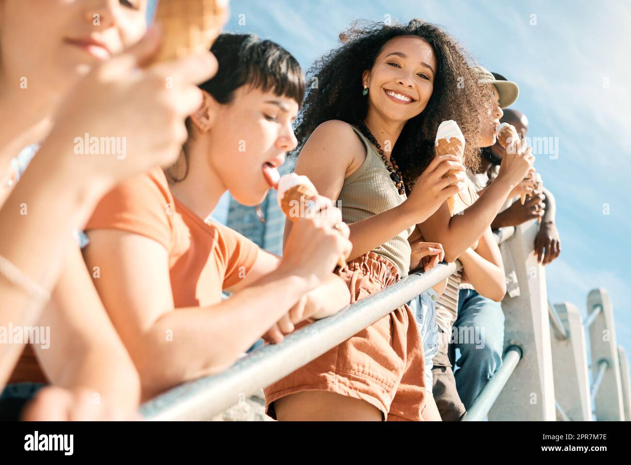 Der beste Tag aller Zeiten. Beschnittenes Porträt einer attraktiven jungen Frau, die mit ihren Freundinnen am Strand ein Eis genießt. Stockfoto