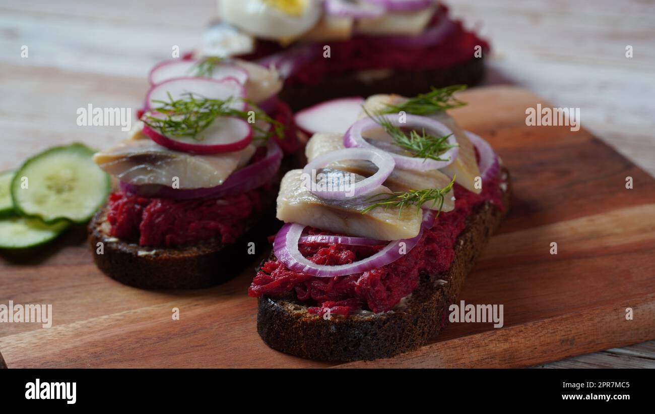 Dänisches offenes Sandwich auf dunklem Roggenbrot mit Hering, Lachs, Rote Beete, roten Zwiebeln und Rettich Stockfoto