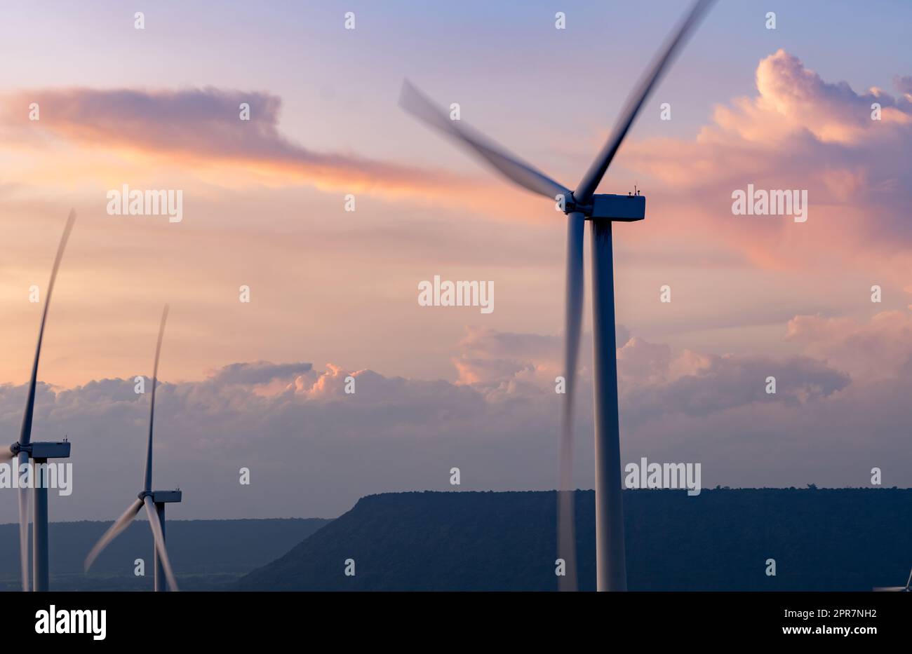 Windenergie. Windkraft. Nachhaltige, erneuerbare Energien. Windturbinen erzeugen Strom. Windmühlen-Farm auf einem Berg mit Sonnenuntergang am Himmel. Umweltfreundliche Technologie. Erneuerbare Ressource. Nachhaltige Entwicklung. Stockfoto