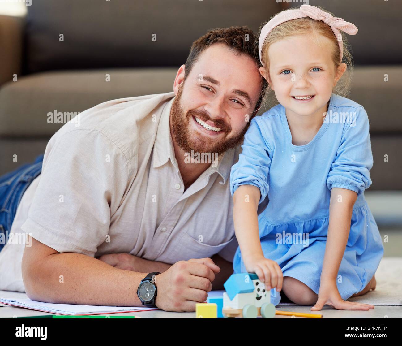 Porträt von Vater und Tochter, die sich zu Hause verbinden. Papa beobachten Tochter spielen mit Spielzeug. Eltern und Kinder lächeln glücklich zusammen zu sein Stockfoto
